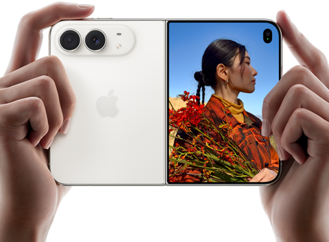 iPhone Duo, Star White colour, held by two hands in horizontal orientation, unfolded, left panel shows 48MP Dual Fusion rear cameras, right panel shows person getting their picture taken on outer display, the subject of the photo is able to see their face as their picture is getting taken using Duo Preview